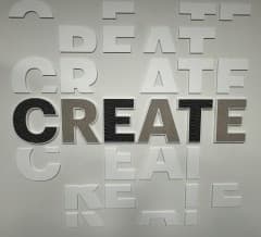 The word ‘CREATE’ in raised 3D lettering on a brushed metal wall.