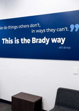 A “This is the Brady way” quote wall in the brand’s blue, above a small seating area.
