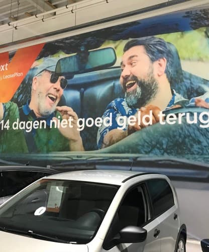 A CarNext showroom mural advertising its 14-day money-back guarantee, a car parked beneath it.