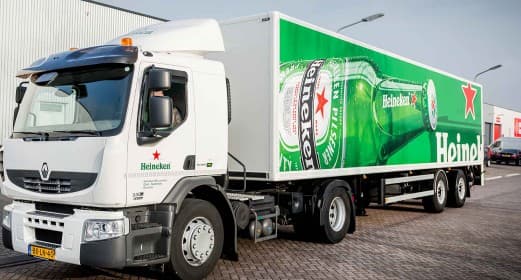 A Heineken-liveried rigid delivery truck parked outside a building, the green bottle graphic wrapping its box body.