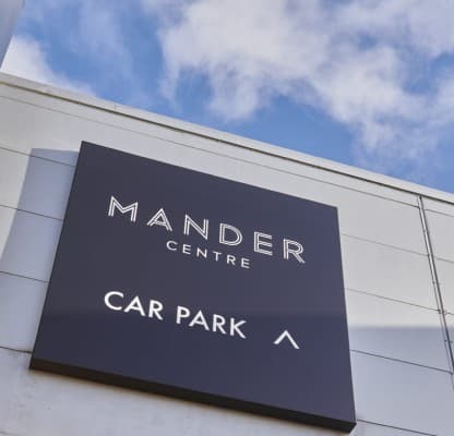 The Mander Centre parking garage sign on the elevation against a blue sky.