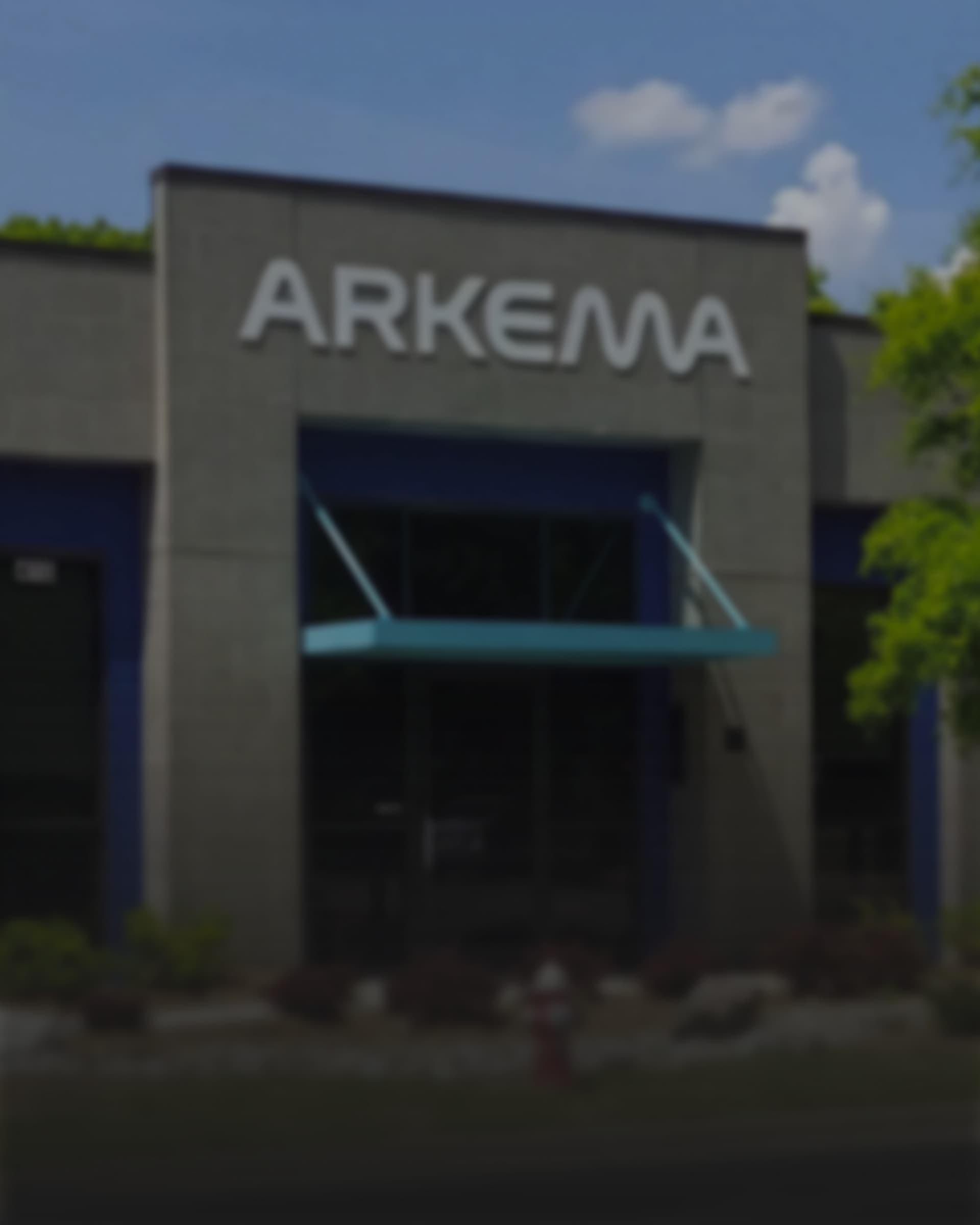 The Arkema wordmark mounted on a building entrance, a glass awning over the doors below.
