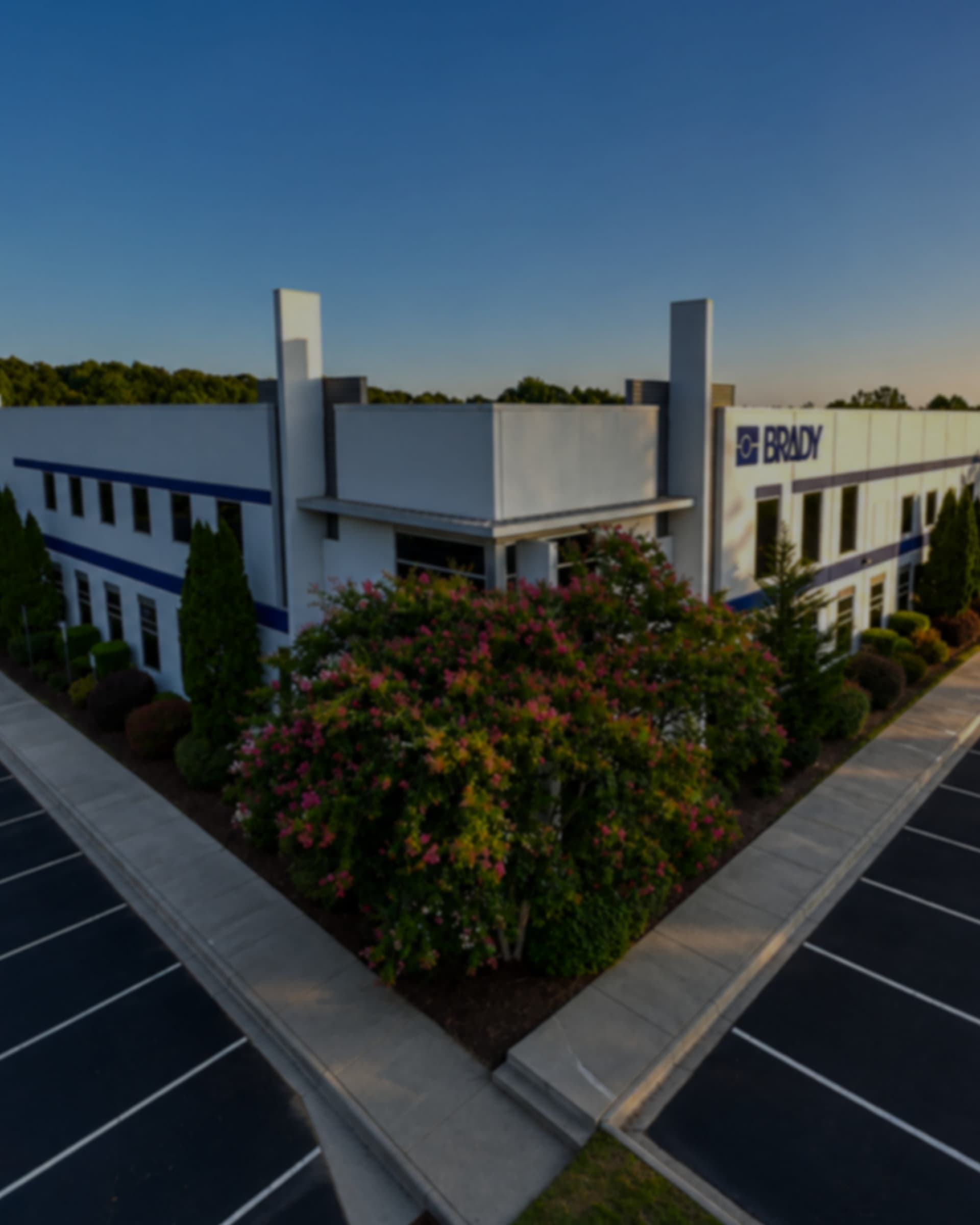 An aerial view of a Brady facility at dusk, the BRADY wordmark on its exterior corner.