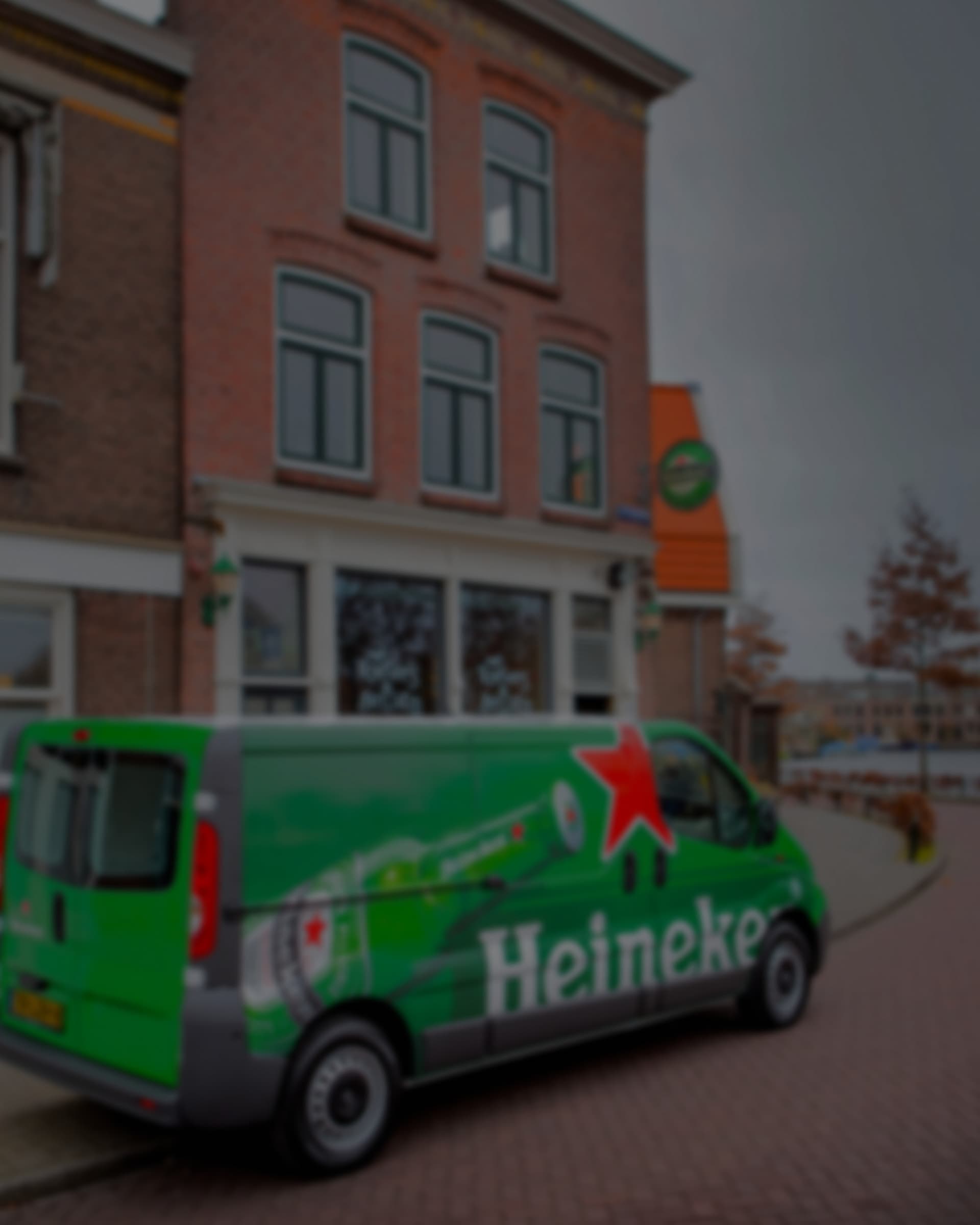 A Heineken-branded van parked on a street outside a brick building.