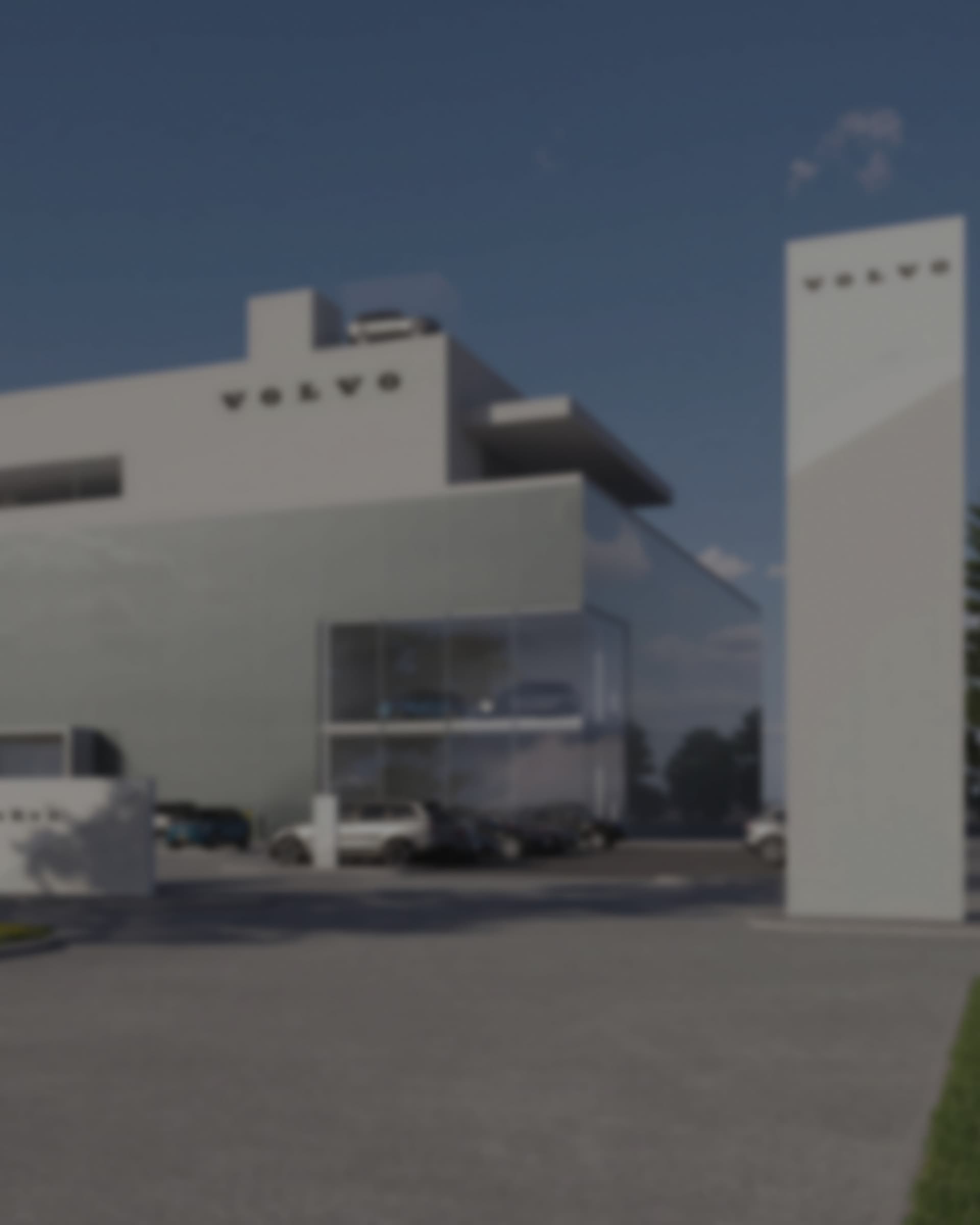 A Volvo dealership building with the wordmark on its facade, a tall branded pylon sign standing beside the forecourt.
