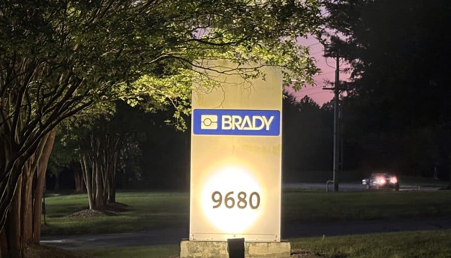 Brady’s illuminated monument sign at the site entrance at dusk.