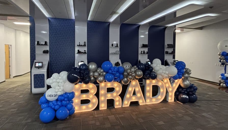 Illuminated BRADY letters in front of the branded showroom wall.