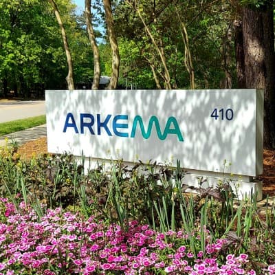 An Arkema monument sign reading '410' surrounded by flowering plants.