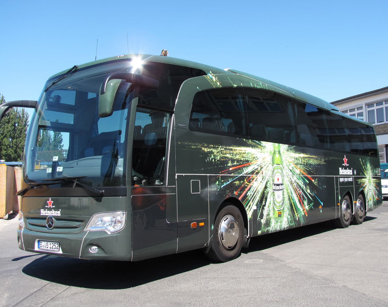 A coach in the dark UEFA Champions League Heineken livery, its green burst graphic along the side.