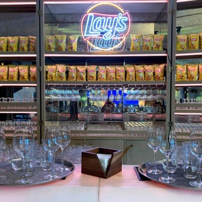 An illuminated Lay’s sign above the tasting bar, packets of Lay’s crisps stacked on the shelves below.