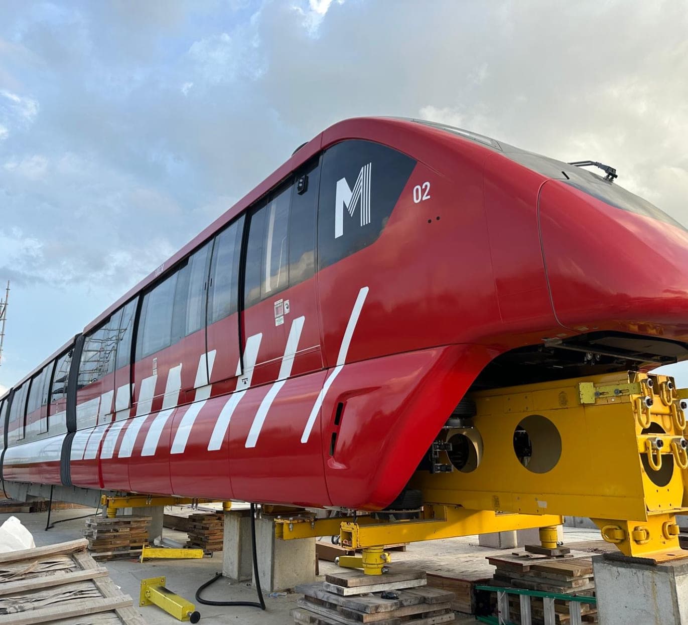 An Alstom metro car raised on jacks at the platform edge, its full-length livery and graphics complete.