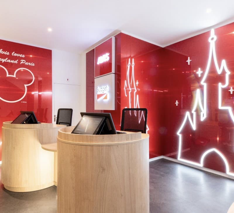 The Avis Budget branch at Disneyland Paris, a line-drawn castle across the red wall.