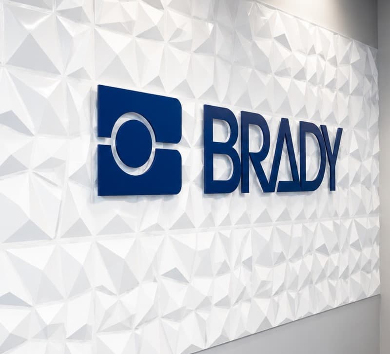 A dimensional BRADY logo mounted on a white textured feature wall.