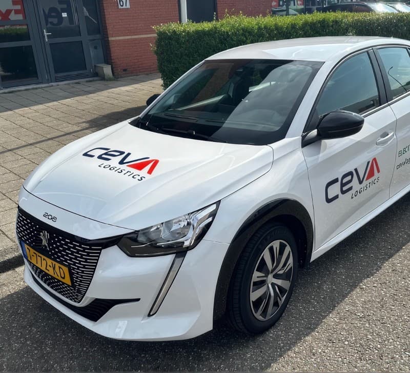A CEVA Logistics electric car in the new livery, parked outside a depot.