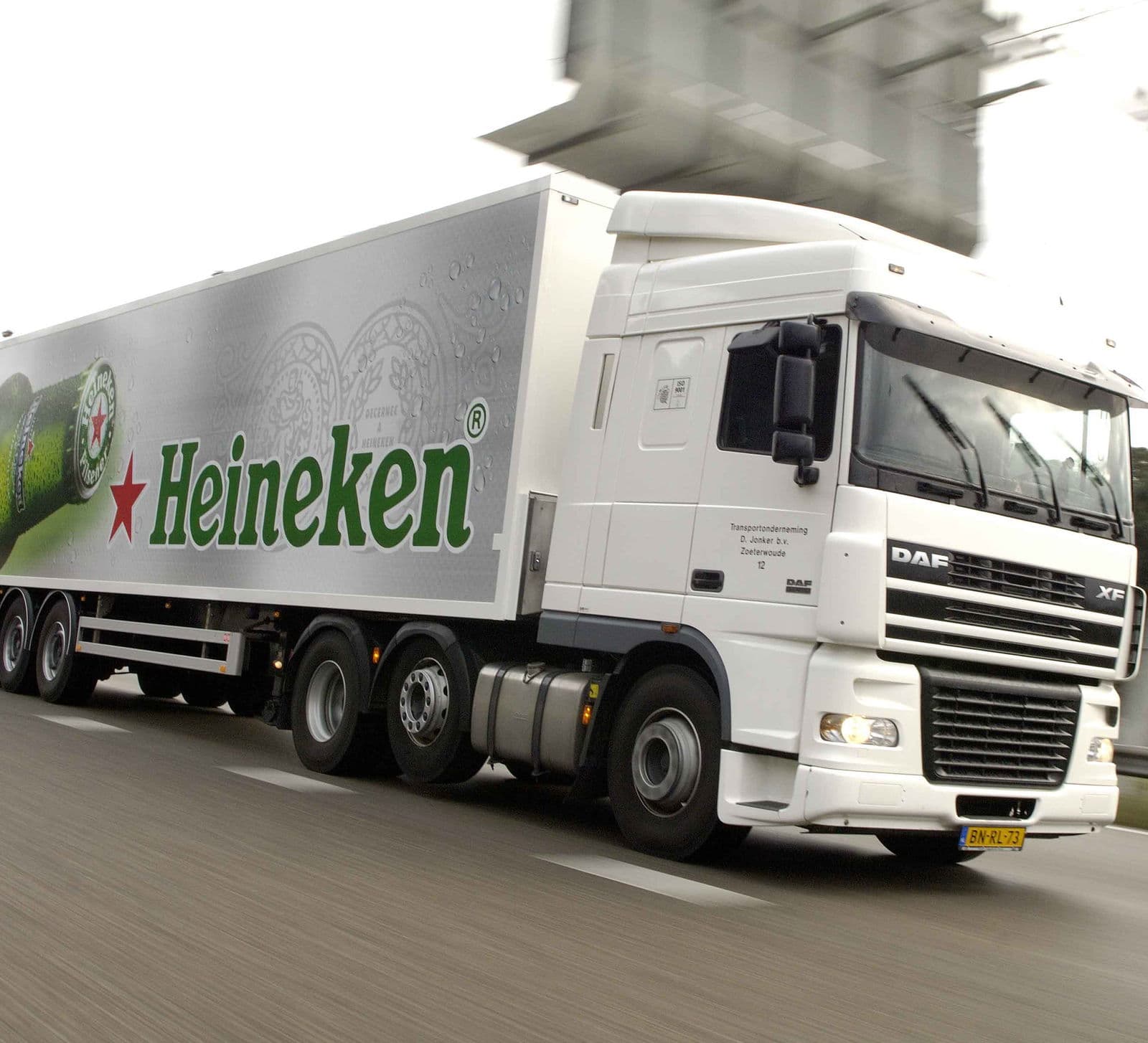 A Heineken tractor unit and trailer at speed on the motorway in the green bottle livery.