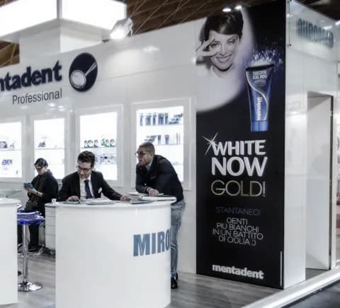 Visitors at a Mentadent Professional stand beside a White Now Gold campaign panel.