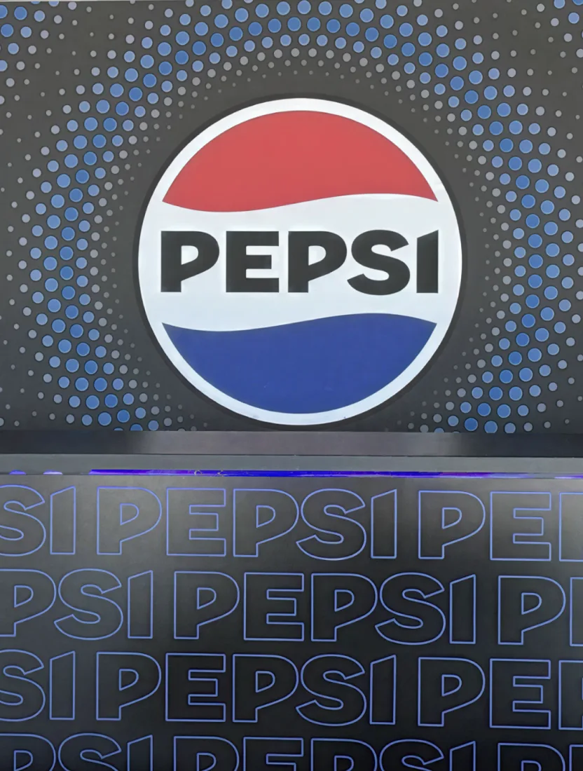 A Pepsi exhibition stand with an oversized illuminated logo above a repeating wordmark wall.