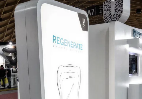 An illuminated Regenerate Enamel Science totem on a trade-show stand.