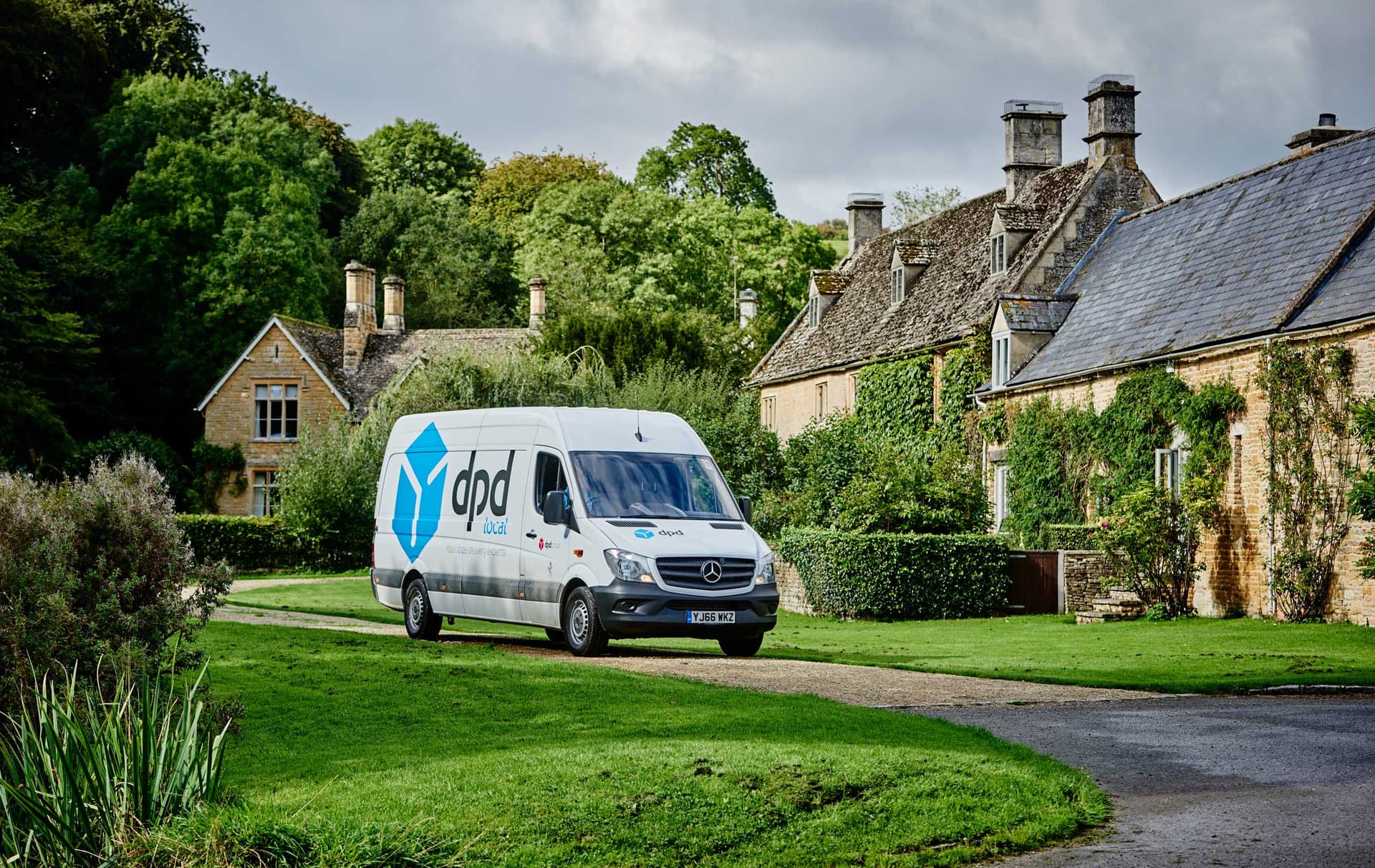 DPD Local delivery van parked on a lane beside Cotswold stone cottages