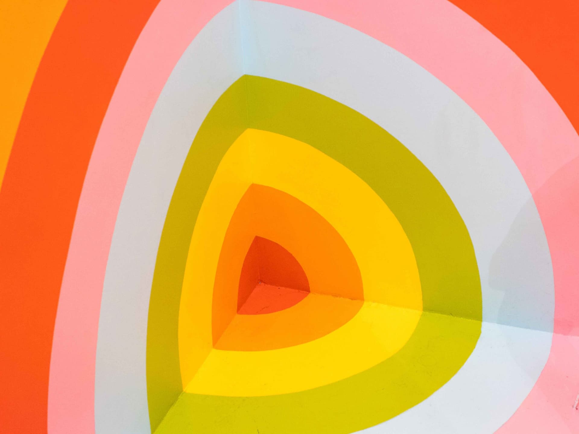 Concentric painted arcs in orange, pink, yellow and grey meeting at a corner